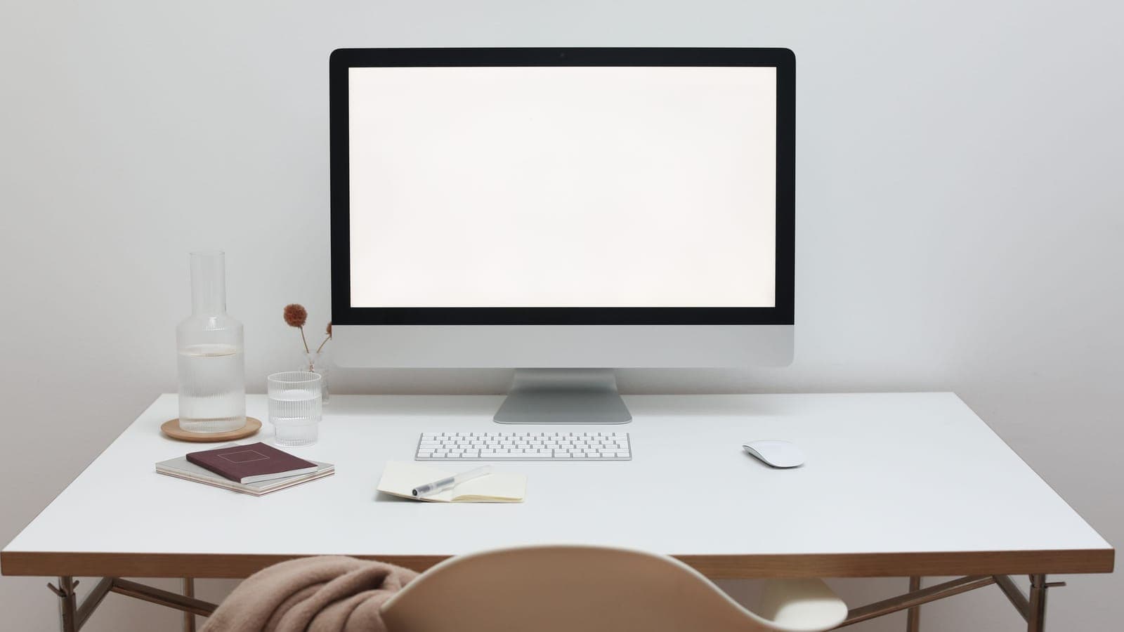 Minimalist white workstation with a desktop monitor displaying enterprise architecture diagrams